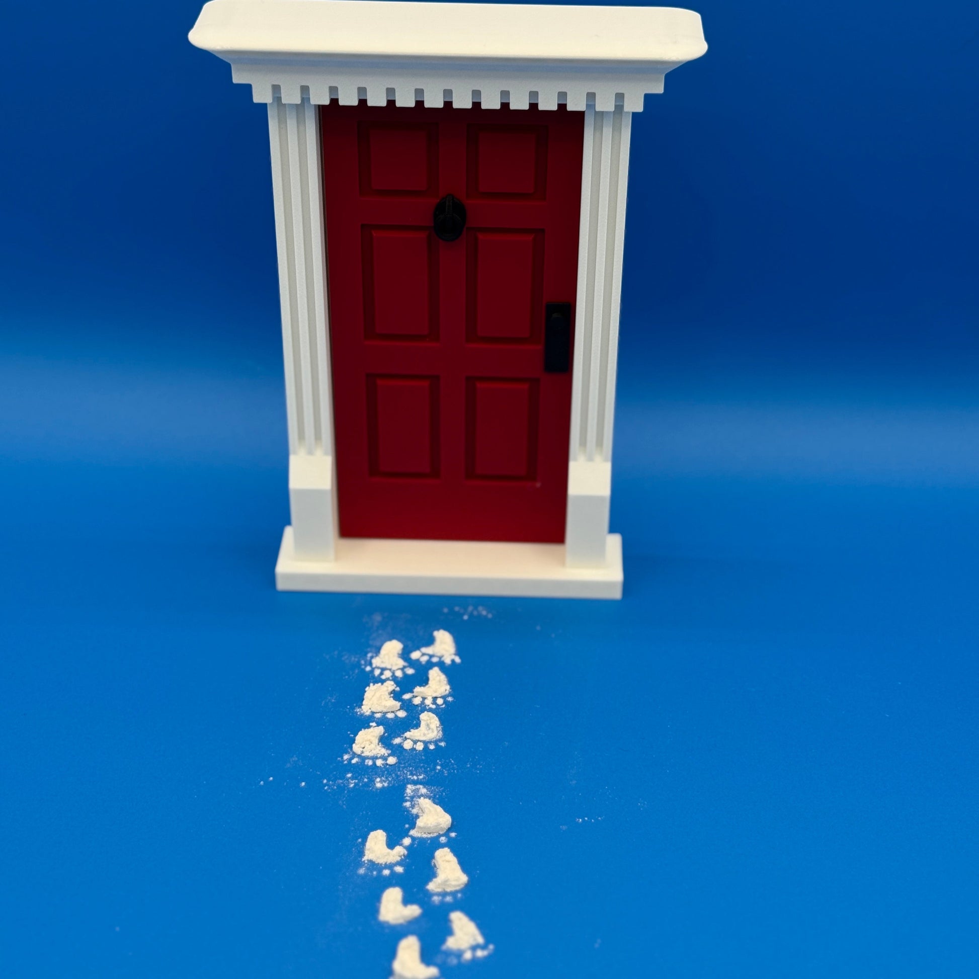 Miniature red elf door with flour footprints made using matching 3D printed stencil