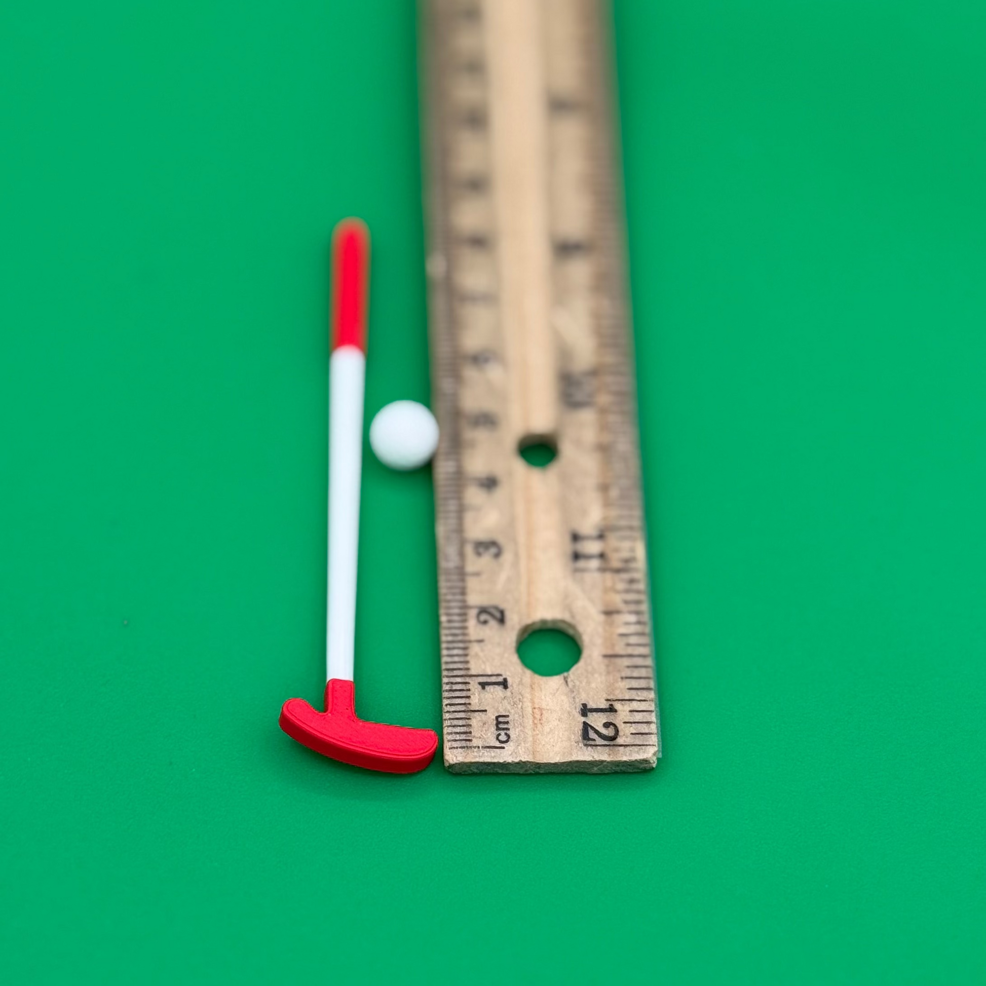 Putter and ball shown next to ruler for scale