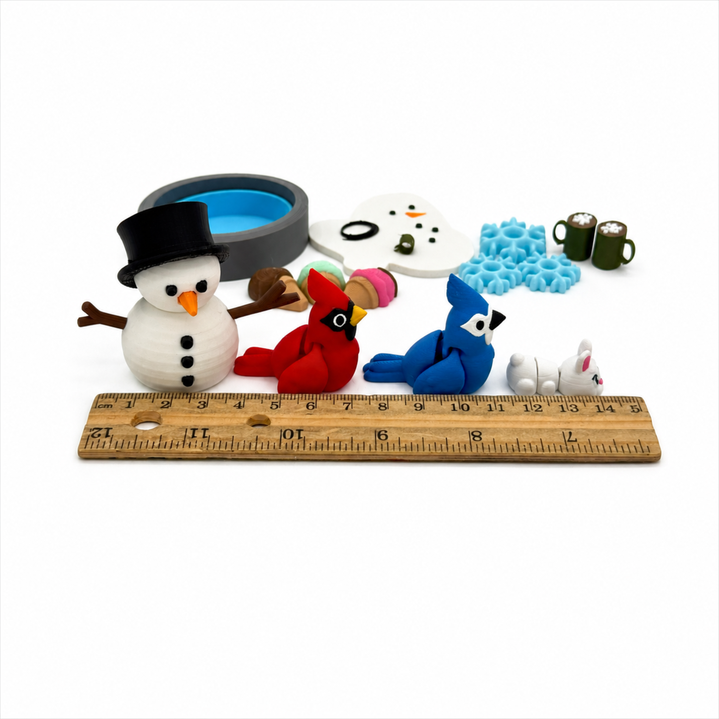 Winter snowman sensory play set shown beside a ruler for size reference, including snowman, cardinal, blue jay, bunny, snowflakes, mugs, and accessories for preschool learning and speech therapy.