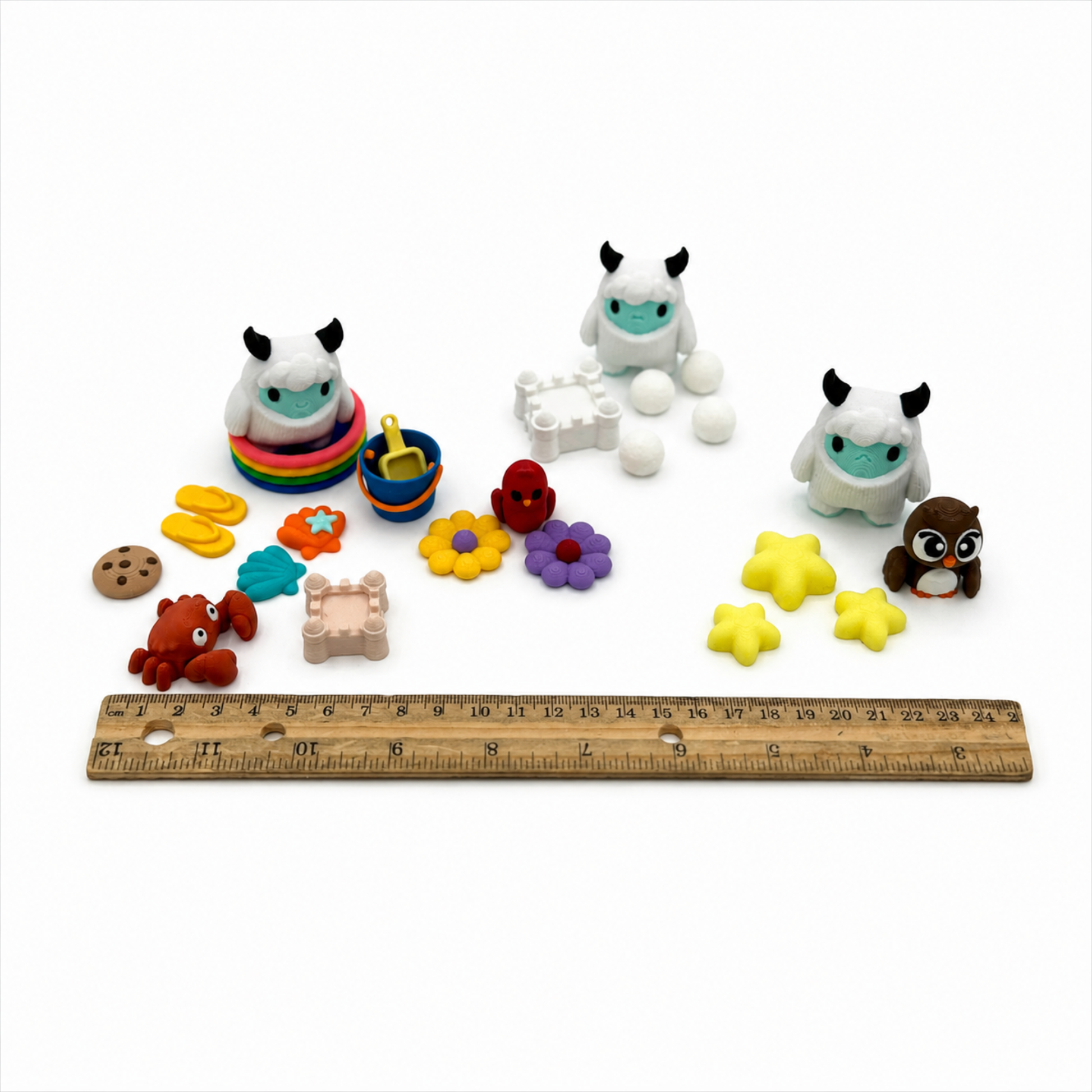 Yeti & Friends sensory play set shown beside a ruler for size reference, including miniature yetis, beach accessories, flowers, stars, owl, and crab for storybook extension activities.