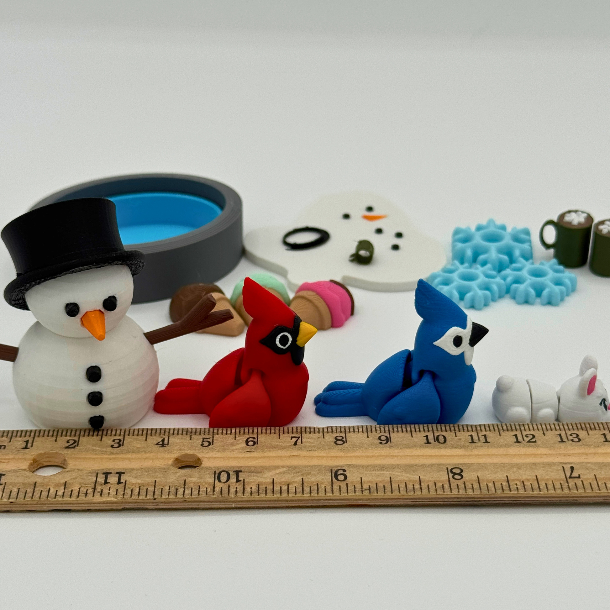 Size reference of small 3D printed snowman and animal figures shown next to a ruler to demonstrate miniature scale